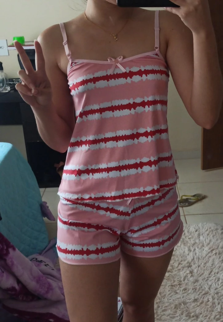 Pessoa tirando selfie no espelho vestindo um conjunto de baby doll rosa com listras brancas e vermelhas.