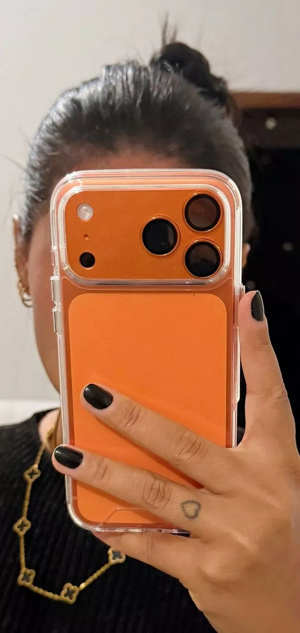 Pessoa segurando iPhone 17 Pro Max laranja com fundo desfocado