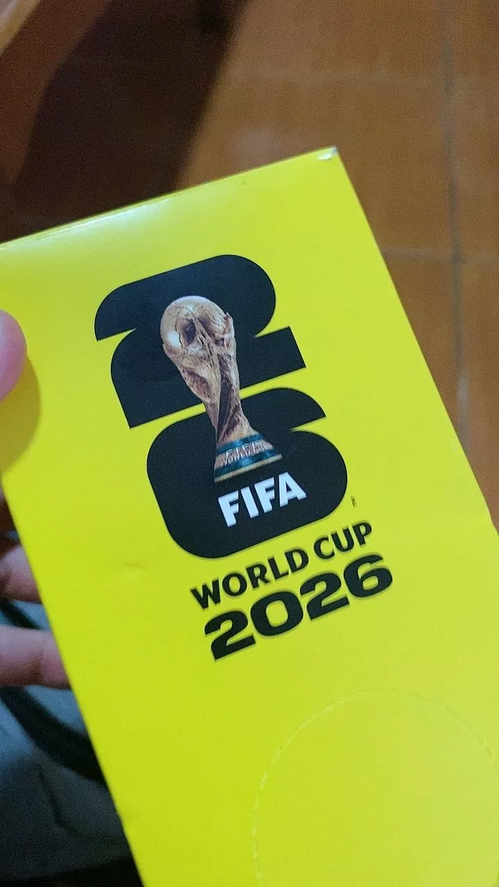 Verso do pacote amarelo com design em preto e branco, destacando o logotipo da FIFA e o título 'WORLD CUP 2026'.
