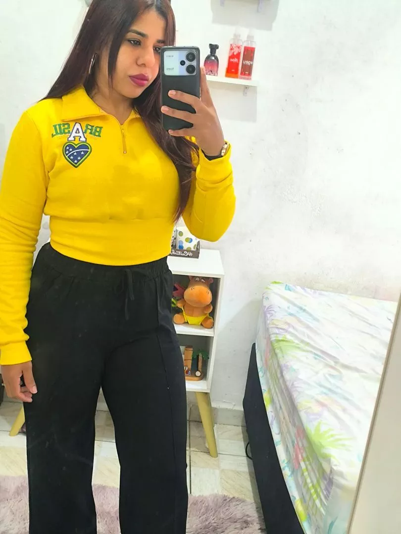 Jovem vestindo cropped amarelo de moletom com zíper e calça preta em frente ao espelho