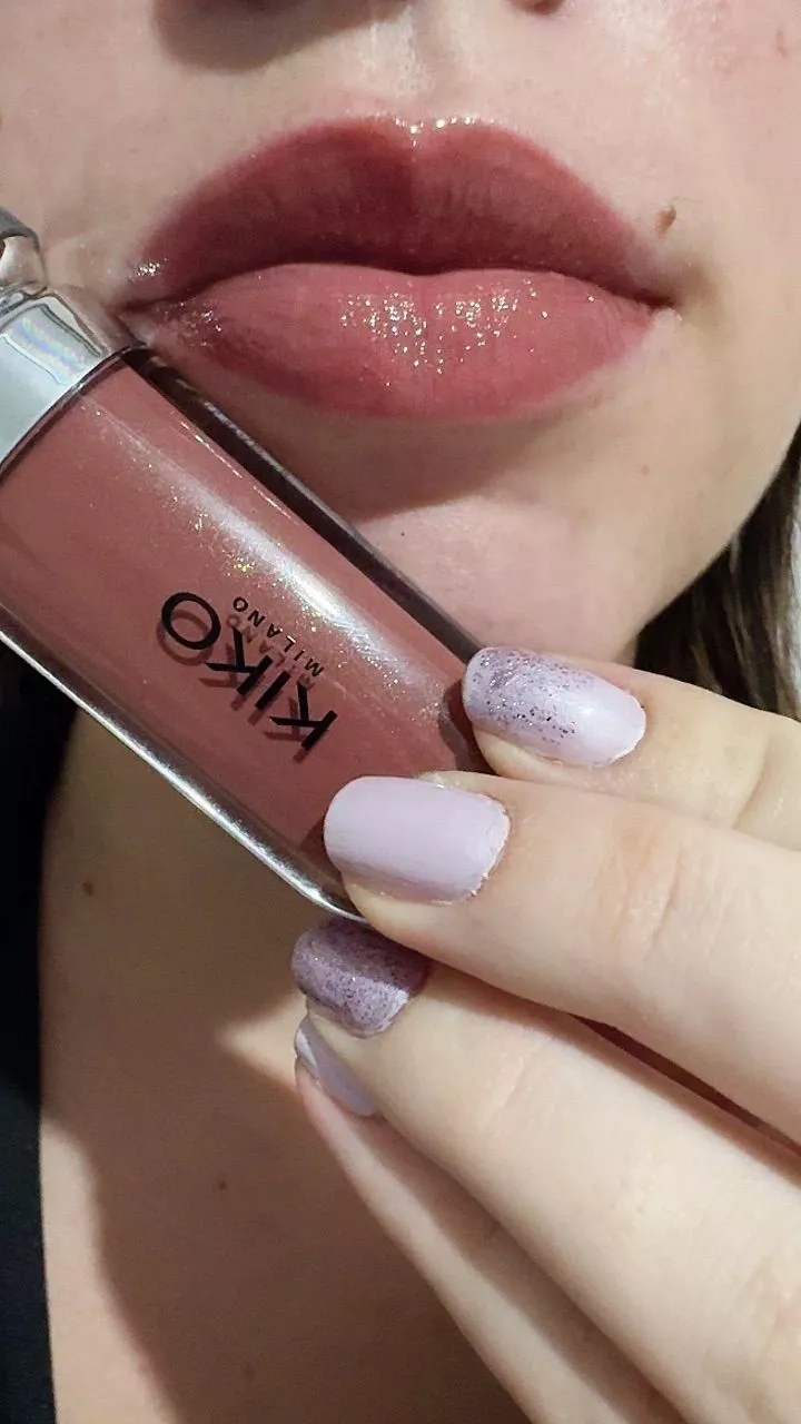 Close nos lábios usando o gloss Kiko Milano segurando a embalagem com unhas pintadas