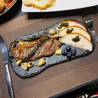 Bandeja de refeição ocidental em placa de pedra natural, prato de bife, prato de sushi, arranjo de sobremesas e bolo para fotografia