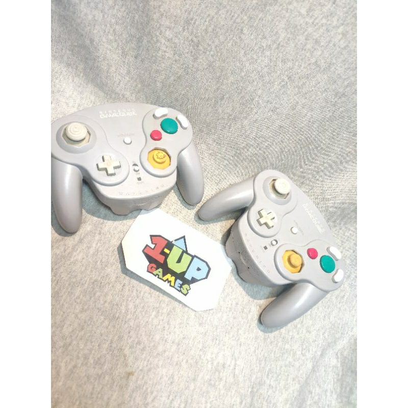par de CONTROLEs WAVEBIRD GAMECUBE. cinza - NINTENDO GAMECUBE. sem o receptor. um está com o manche faltando a parte