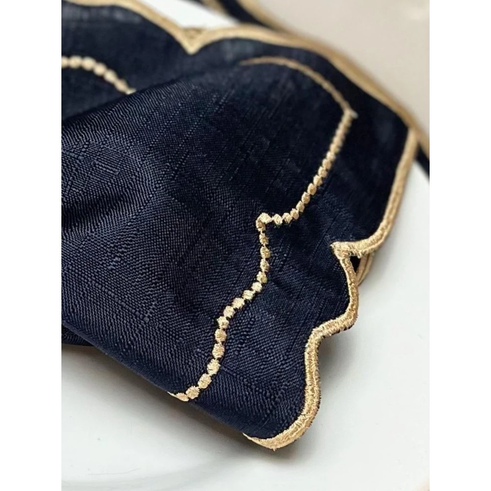 Detalhe em close do bordado dourado e textura do tecido azul marinho do jogo americano