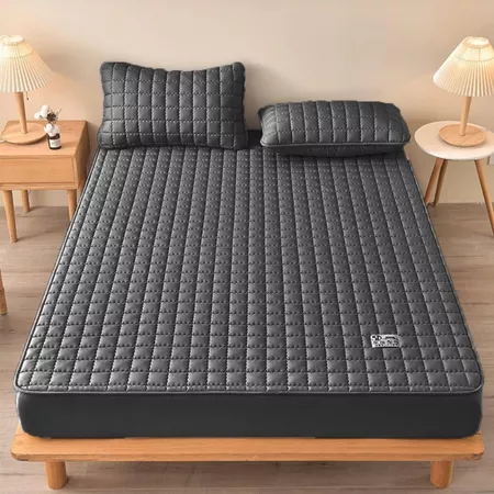 Capa de colchão impermeável matelada cinza em uma cama de solteiro com travesseiros.