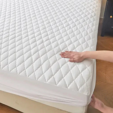Mão colocando capa de colchão branca matelada em um colchão.