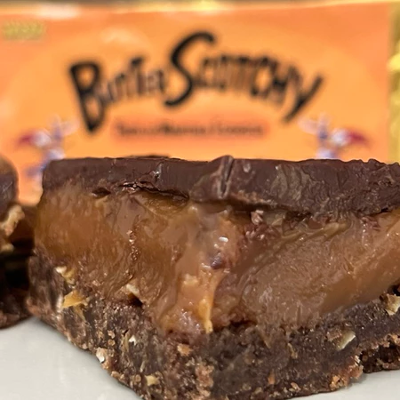 Close-up de um pedaço de Butter Scotchy, com embalagem ao fundo