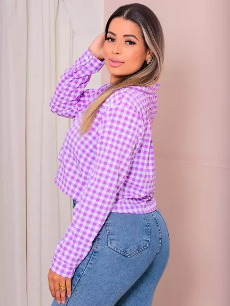 Mulher de perfil exibindo camisa cropped xadrez lilás e branca de manga longa com botões