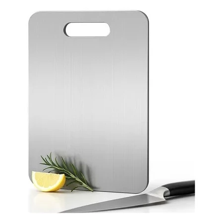 Tábua de corte em aço inoxidável com uma fatia de limão e um ramo de alecrim ao lado, com uma faca de cozinha em primeiro plano.