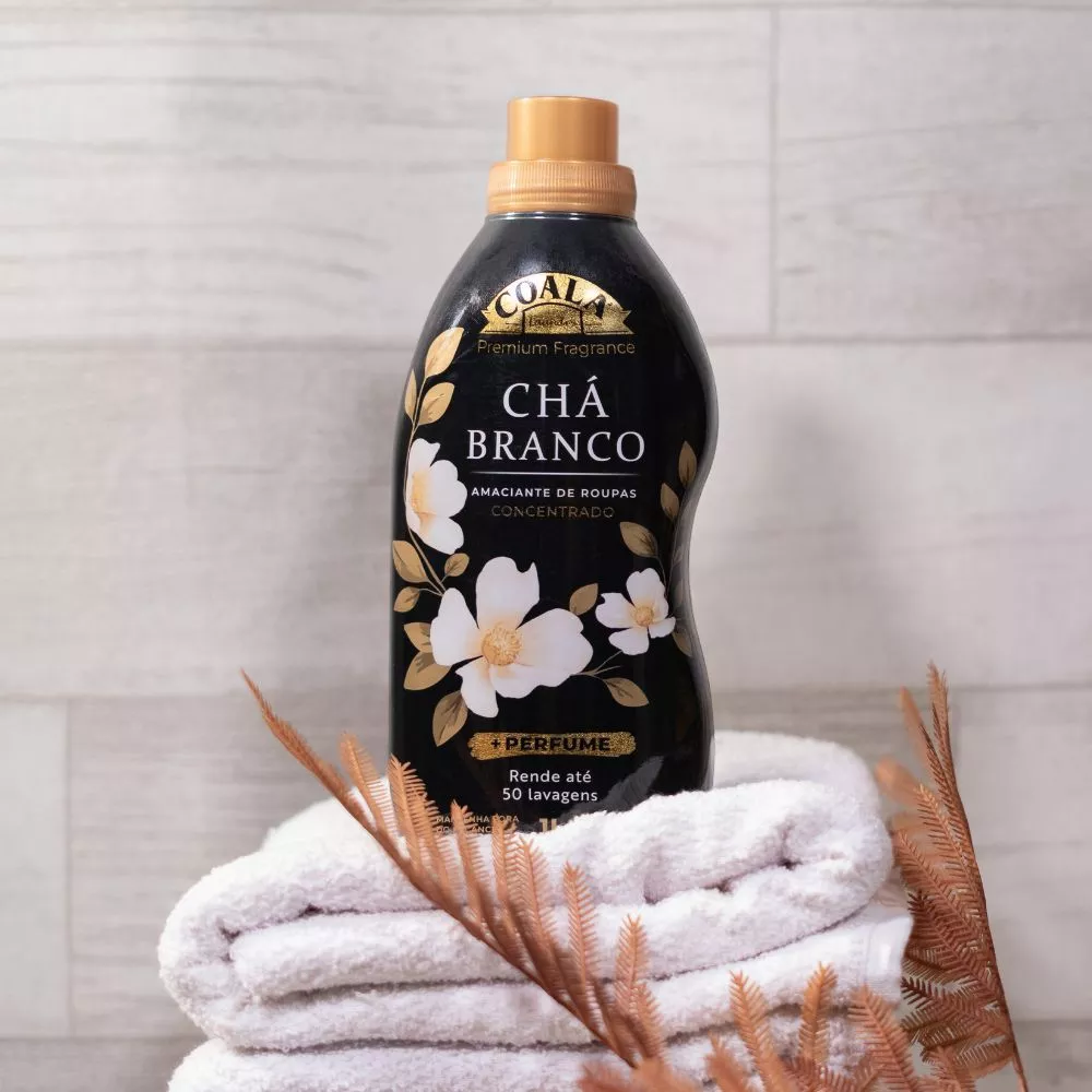 Um frasco de amaciante Coala Laundry Chá Branco posicionado sobre uma pilha de toalhas brancas dobradas