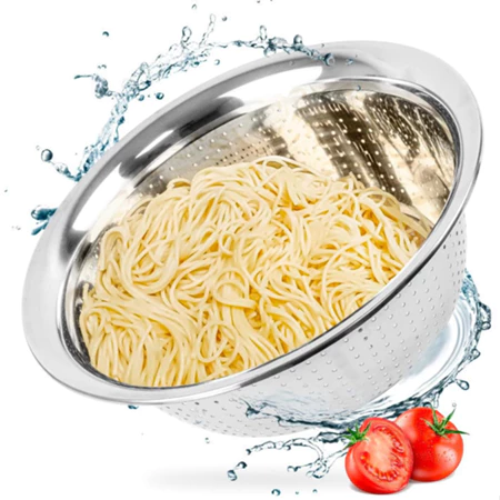 Escorredor de aço inox contendo macarrão cozido, cercado por efeitos de respingos de água e tomates frescos ao lado