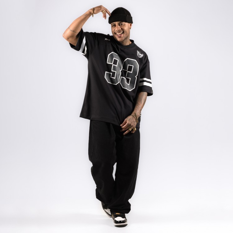 Black oversized football jersey worn with loose black pants and sneakers