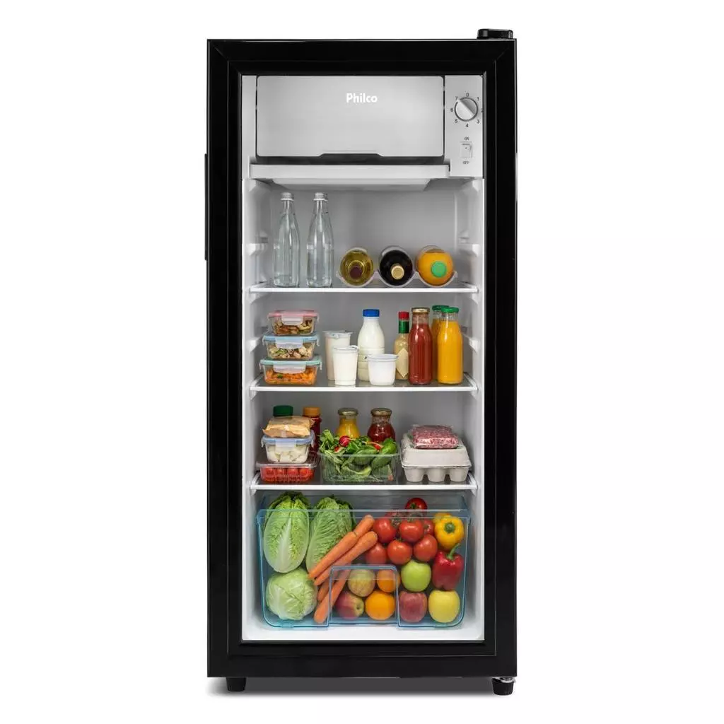 Interior do frigobar Philco 85L organizado com garrafas de bebidas, mantimentos e vegetais na gaveta inferior