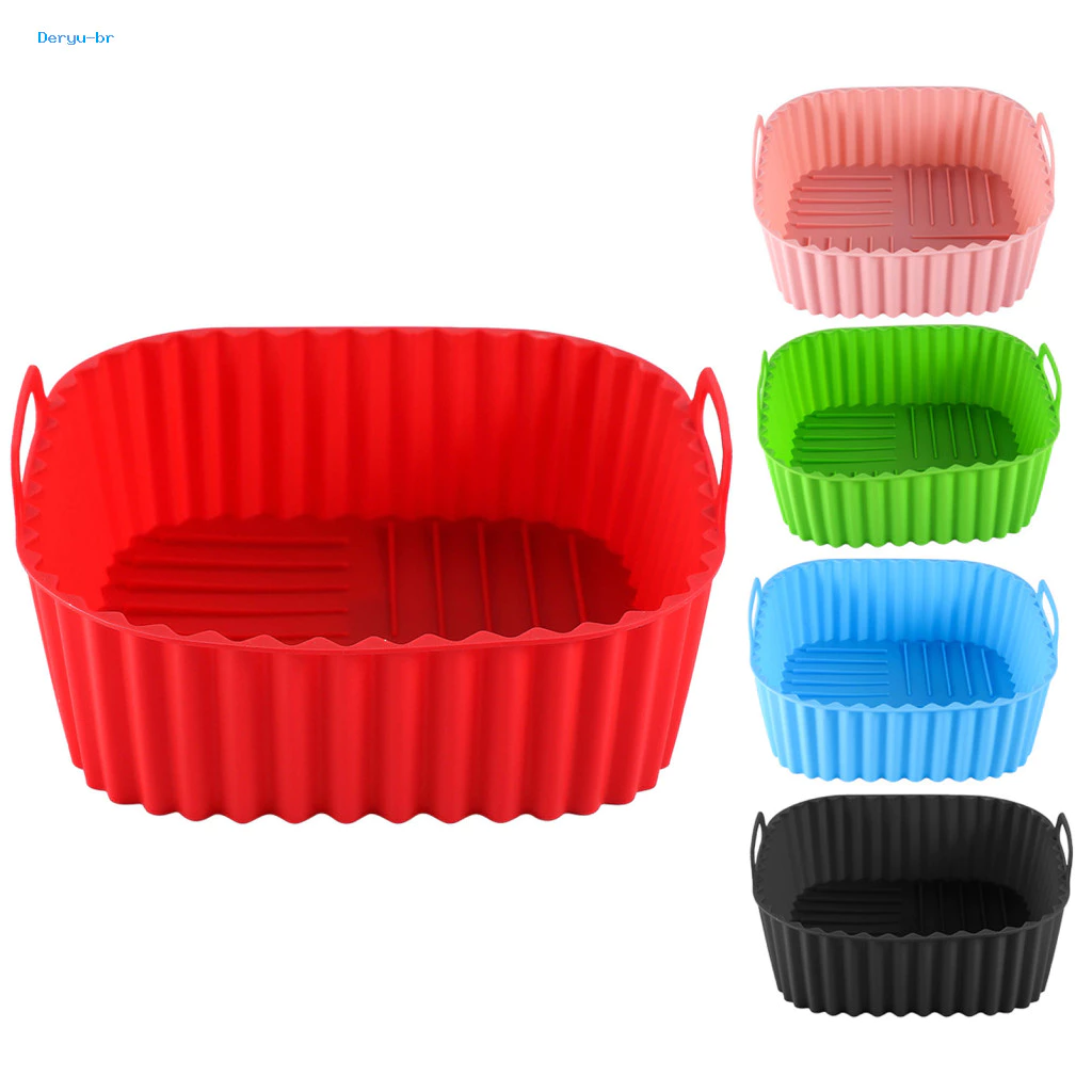 Conjunto de formas de silicone reutilizáveis para air fryer em diferentes cores. Em destaque, à esquerda, uma forma vermelha grande de formato quadrado com bordas arredondadas, laterais caneladas e pequenas alças laterais. À direita, em tamanho menor, a mesma forma é exibida nas cores rosa, verde, azul e preto. O fundo é branco.